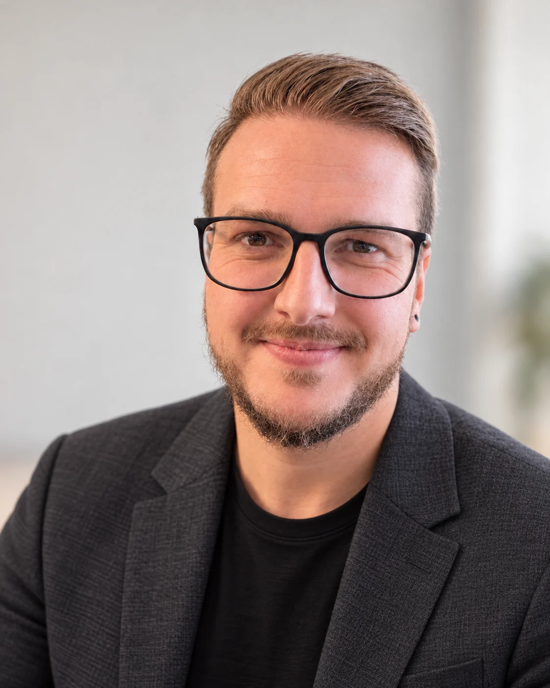 Mario Dornegger, Inhaber von dornegger media, im Porträt mit Brille, schwarzem T-Shirt und grauem Sakko.